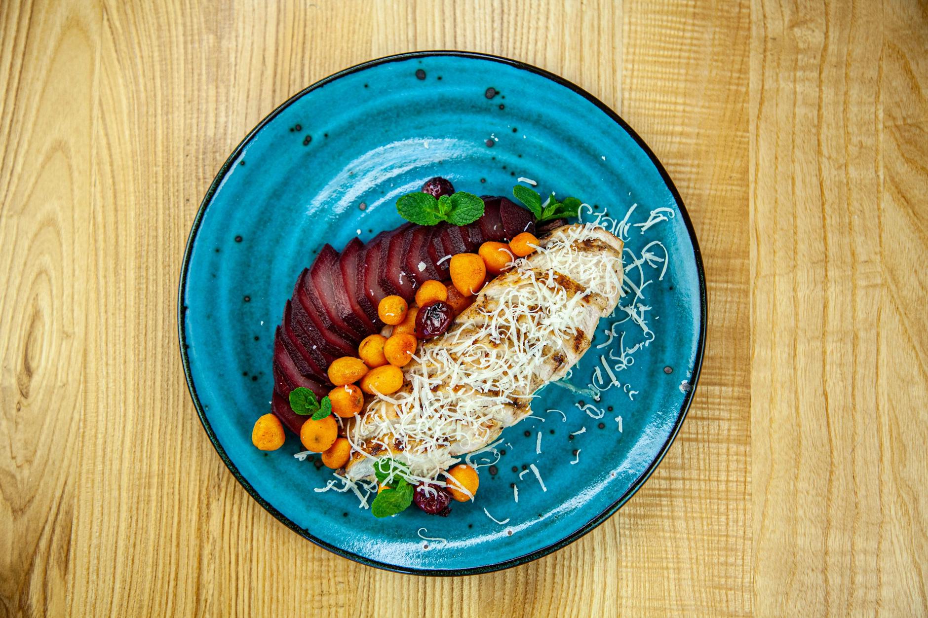 Grillowana pierś kurczaka z warzywami i serem na niebieskim talerzu